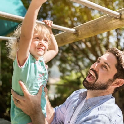 A father holding his child onto the monkey bars at Walnut Creek Apartments in Macon, Georgia