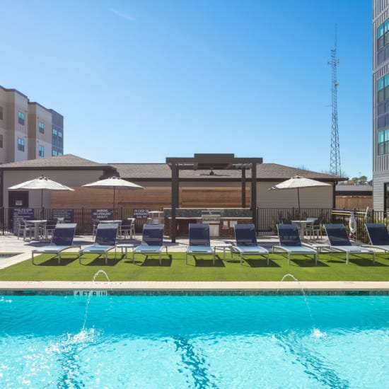 Beautiful inground community pool with umbrellas and lounge chairs at Bellrock Memorial in Houston, Texas