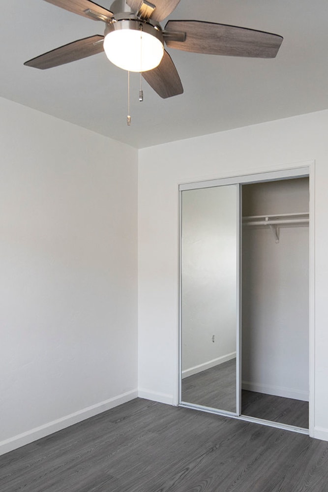 Bedroom photo showing mirrored closet doors and ceiling fan 