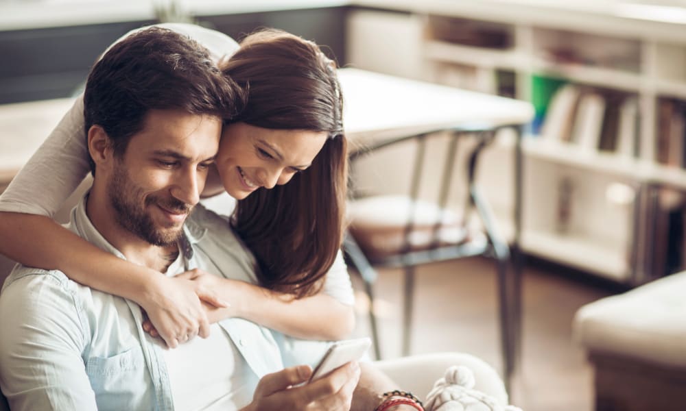 Resident couple connecting with us on social media on a mobile device in their new home at Sofi at Topanga Canyon in Chatsworth, California