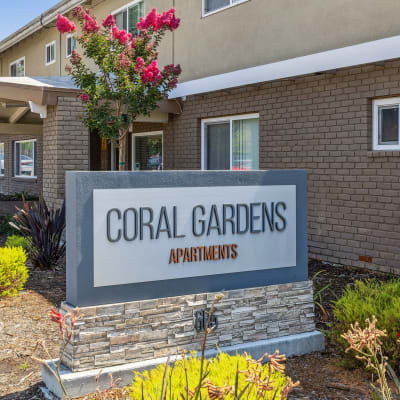 Monument sign and front of building at Coral Gardens Apartment Homes in Hayward, California