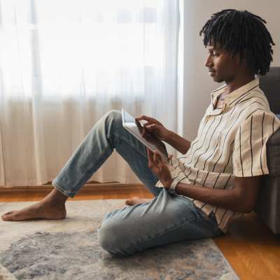 Man using tablet on living room floor at Treehaven in Summerville, South Carolina
