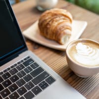 A laptop, cup of coffee and baked treat on a table at The Courts of Avalon in Pikesville, Maryland