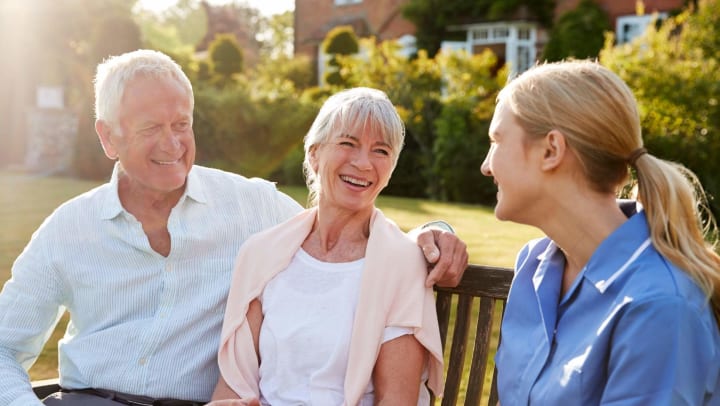 Senior couple talking with nurse and smiling