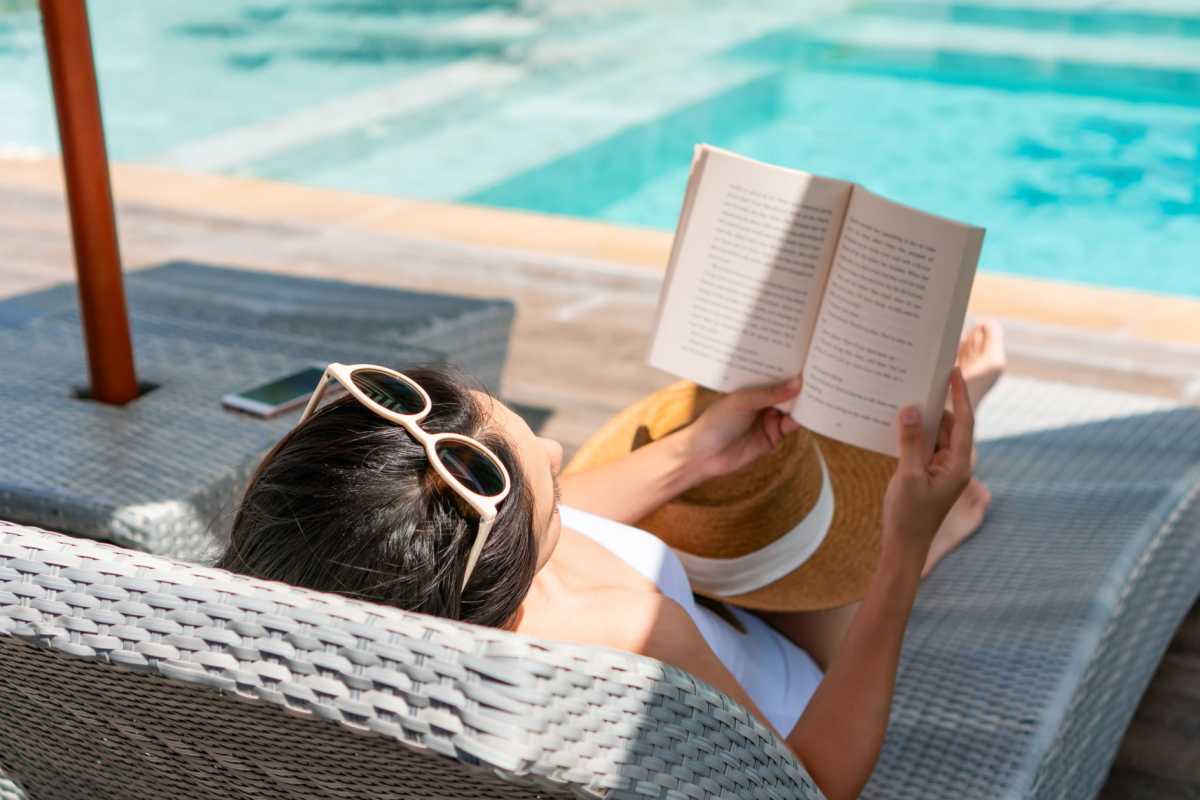 Woman reading book on lounge chair beside pool at Fieldstone in Olathe, Kansas