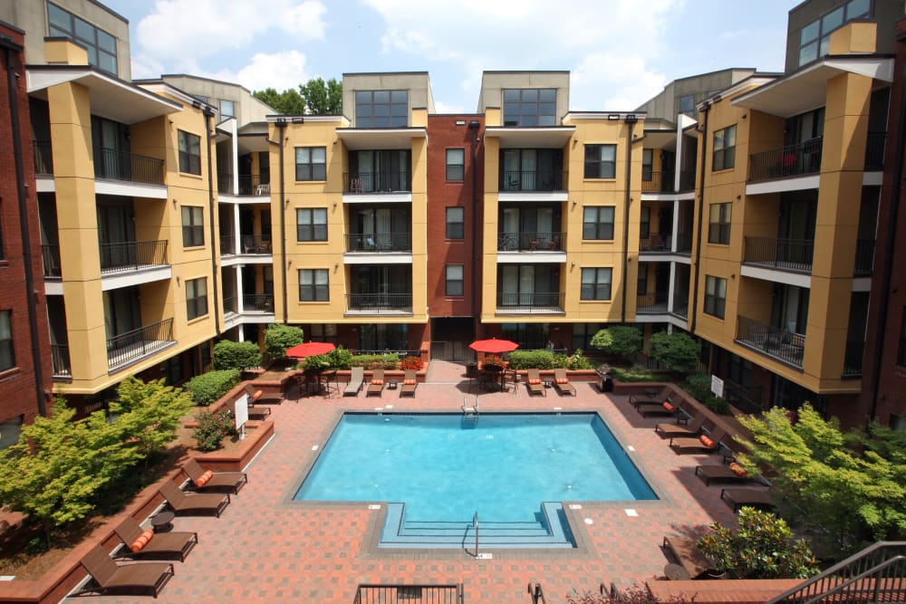 Swimming pool surrounded by lounge chairs and tables with umbrellas in the courtyard at Cielo in Charlotte, North Carolina