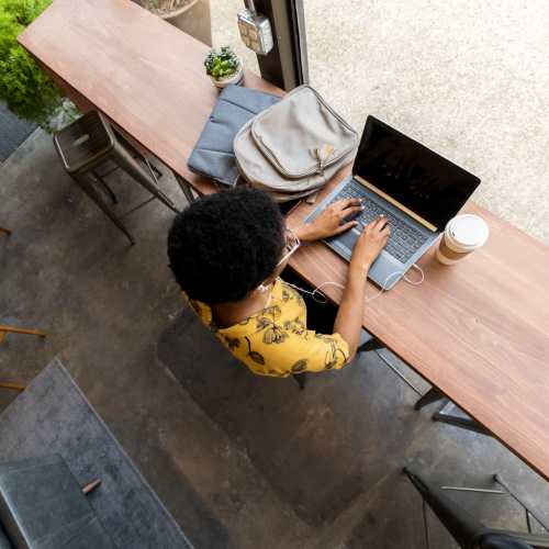 Woman sipping coffee and working at a café near Ludlam Point in Miami, Florida