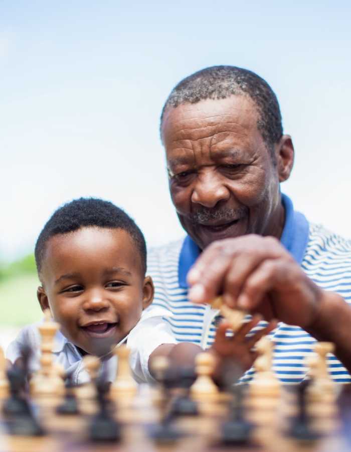Grandparent teaching grandson to play chess at Clearwater at The Arboretum in Austin, Texas