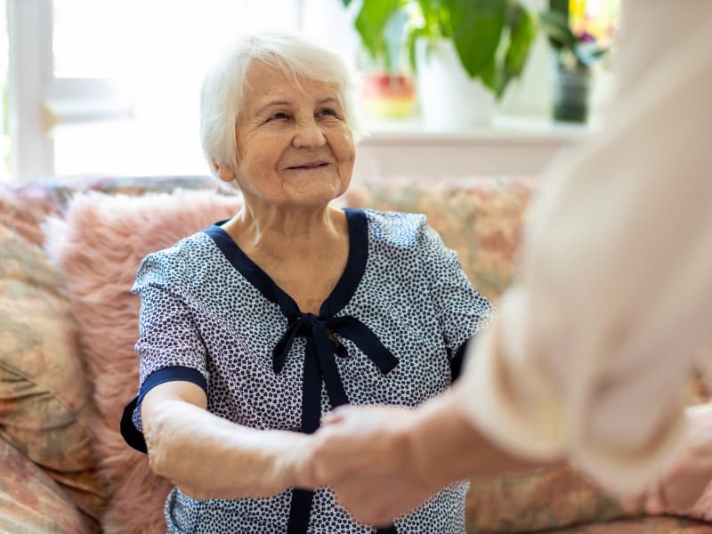 A resident holding hands with a team member at Woodland Palms Memory Care in Tucson, Arizona. 