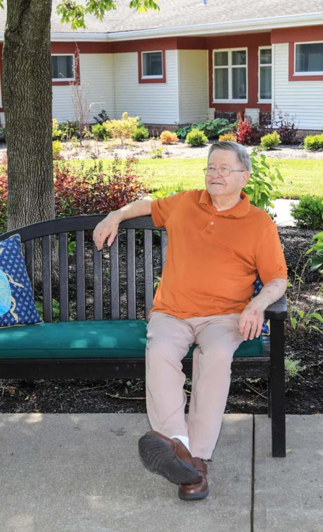 Resident playing outside on a bench enjoying the gardens at O'Fallon in O'Fallon, MO