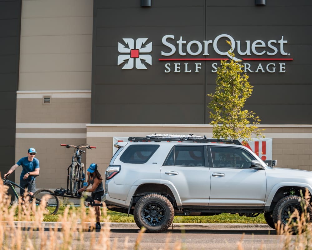Two customers load their bikes onto a car that they store at StorQuest Self Storage