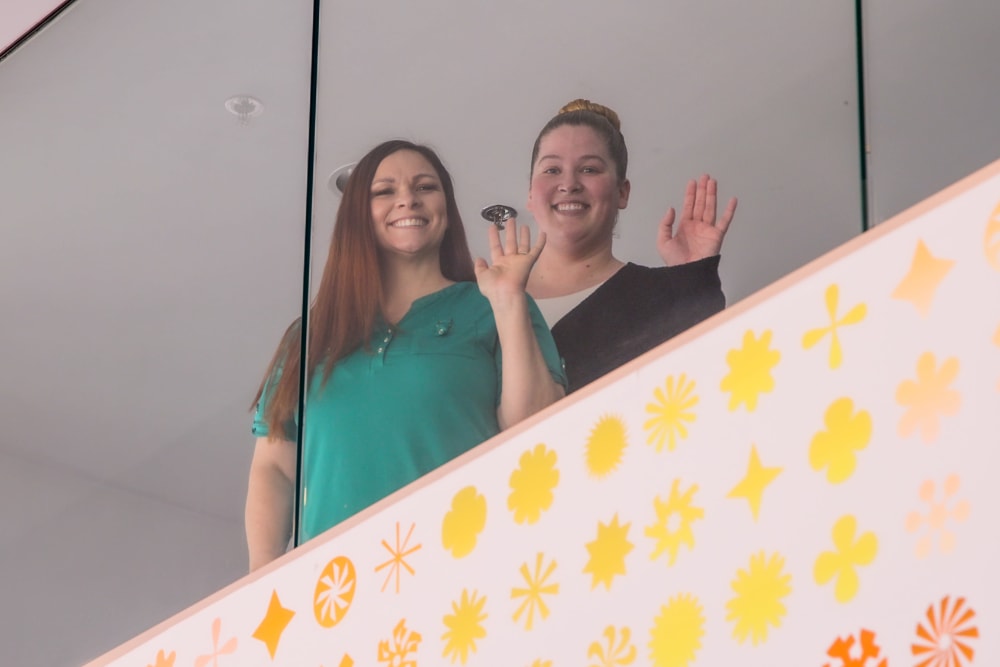 Two employees waving on the stairs at Pillar Properties in Seattle, Washington