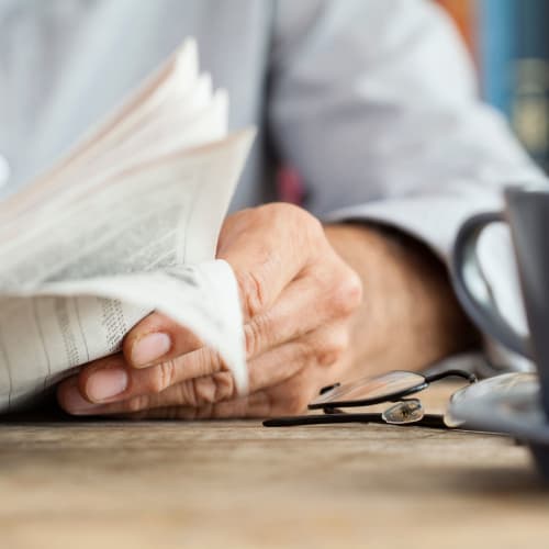 Close-up view of a hand holding a newspaper at The Pillars of Lakeville in Lakeville, Minnesota