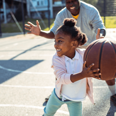 A child and her father playing basketball at Capeharts in Ridgecrest, California