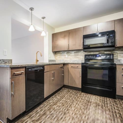 Open concept model kitchen with granite countertops and hardwood-inspired flooring at Greenwood Cove Apartments in Rochester, New York