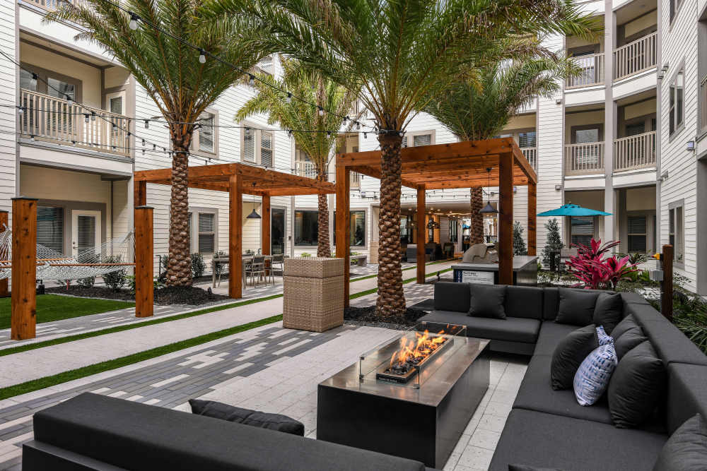 Outdoor grilling area with sectional seating at Soba Apartments in Jacksonville, Florida