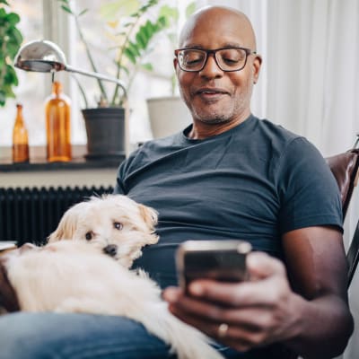 Resident on his phone while his dog sits on his lap at Echelon at Odenton in Odenton, Maryland