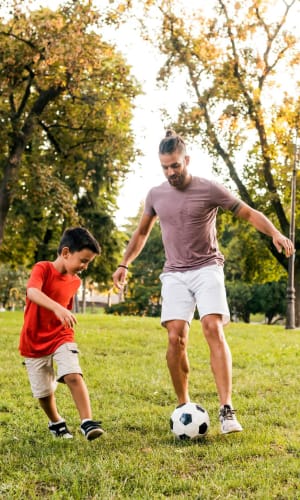 Father and son playing soccer in a park near Bent Creek Apartments in Lewisville, Texas