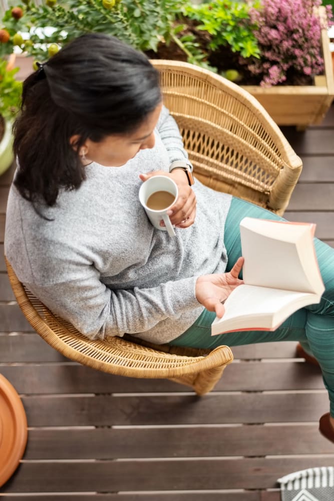 Resident reading on her balcony at Norwalk Towers Apartments in Norwalk, California