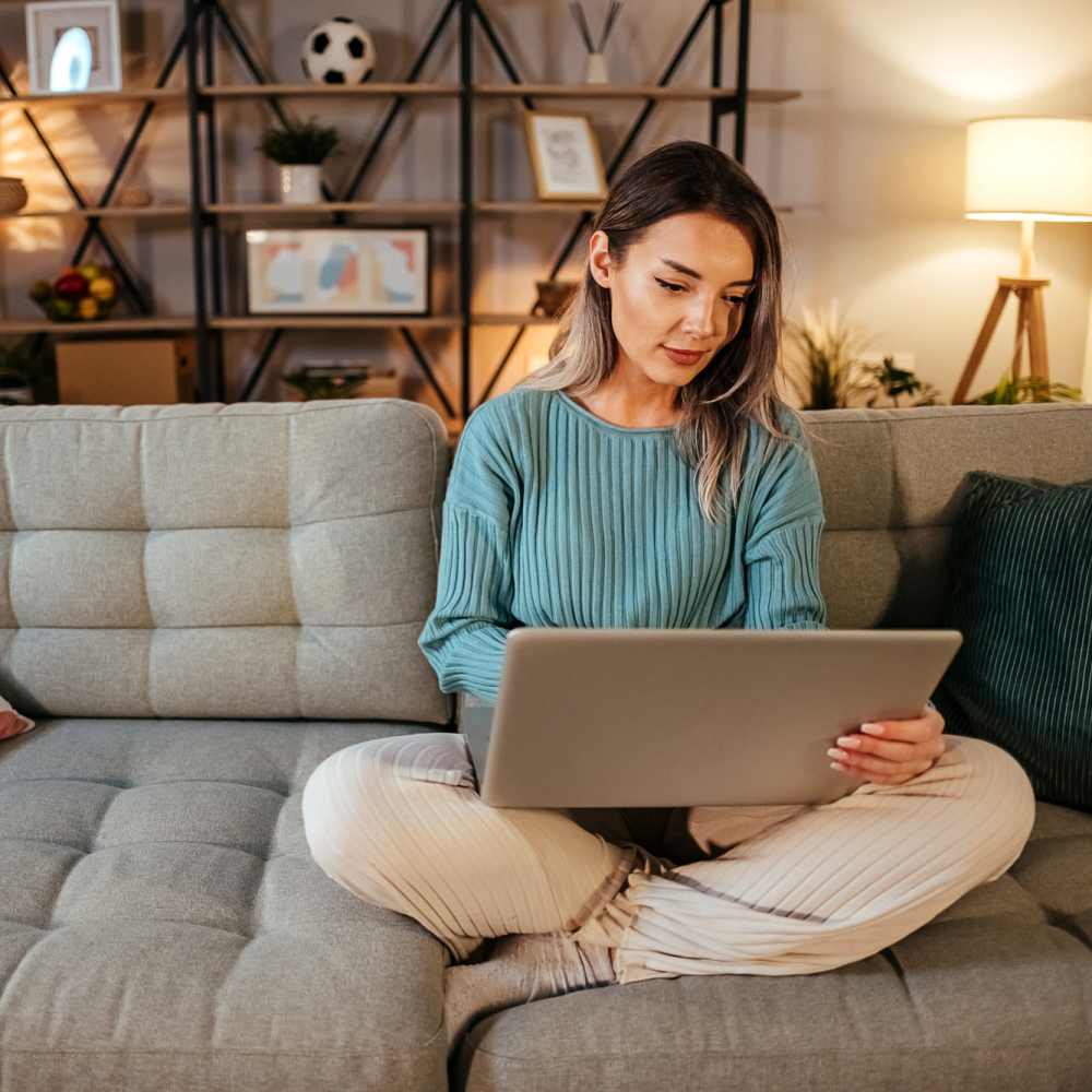 Resident siting on a couch with her laptop at Bana At Tujunga in Tujunga, California