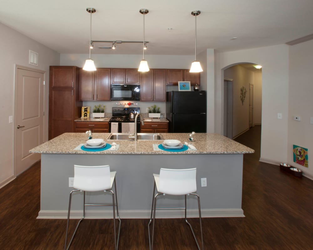 Open-concept model home's kitchen with hardwood floors and breakfast bar at Olympus Katy Ranch in Katy, Texas