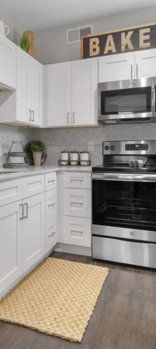 Modern kitchen with stainless steel appliances and wooden floor at Flatiron District at Austin Ranch, The Colony, Texas