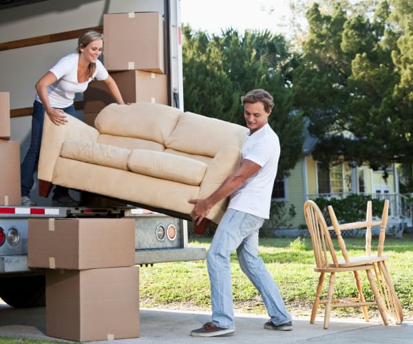 Couple moving couch off of moving truck