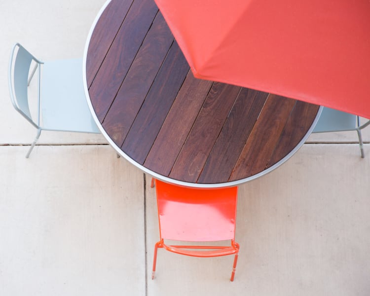 Overhead view of an umbrella providing shade for a table and chairs at Sofi Belmont Glen in Belmont, California