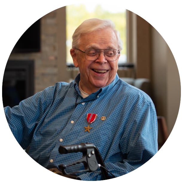 Resident sitting besides a walker smiling inside Sawtooth Ridges Apartments