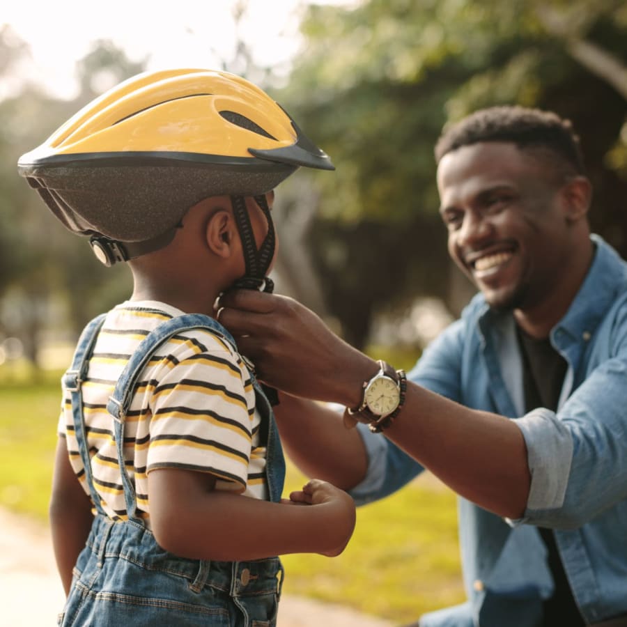 Father putting a bike helmet on his child near Park Terrace in High Point, North Carolina