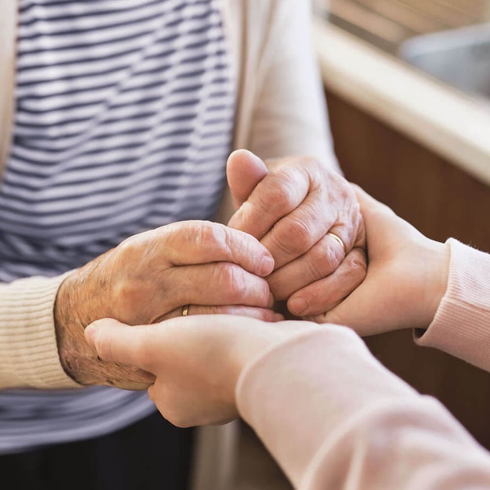 Resident holding hands with a caretaker at Anthology of Millis in Millis, Massachusetts