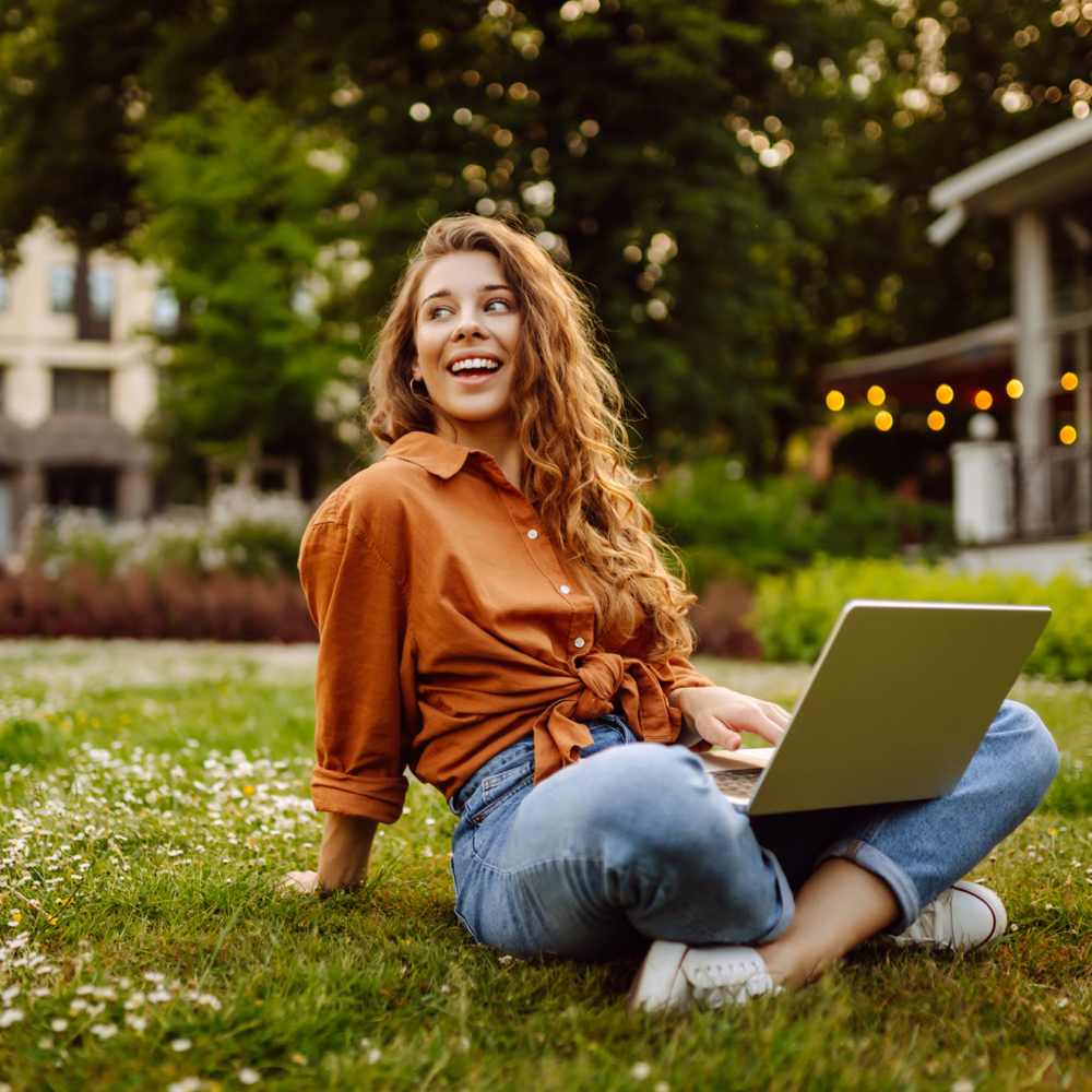 Girl sitting in the park with her laptop open near Vintage Park in Houston, Texas