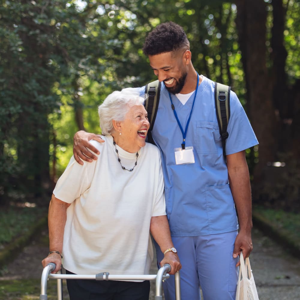 A staff member walking alongside a resident pushing a walker at Greenfield Estates in Akron, Ohio