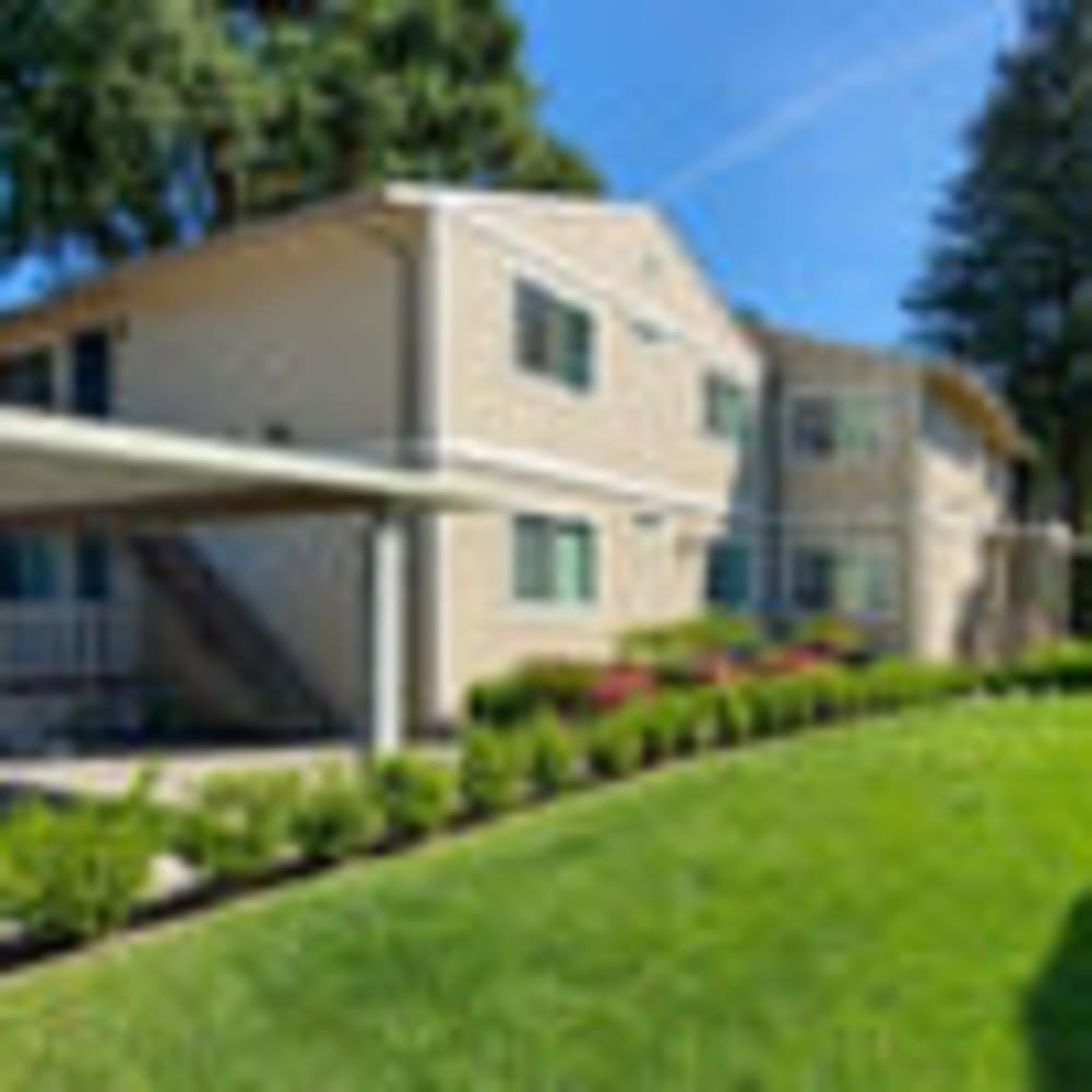 Exterior view of resident buildings with mature trees and lush landscaping at our Redwood Manor community at Mission Rock at Sonoma in Sonoma, California