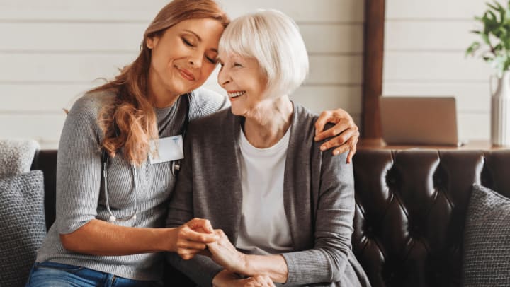 a senior lady and her caregiver hugging each other