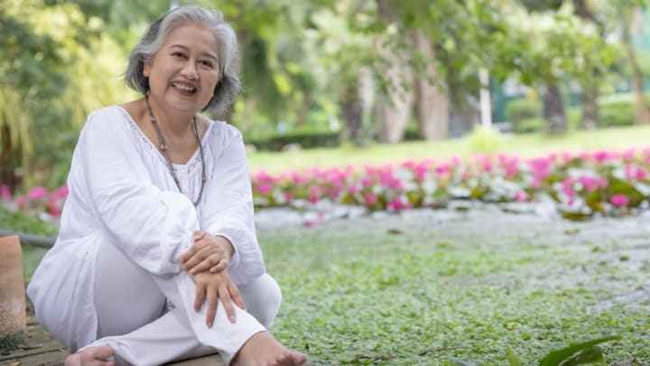 an old woman sitting in a garden smiling