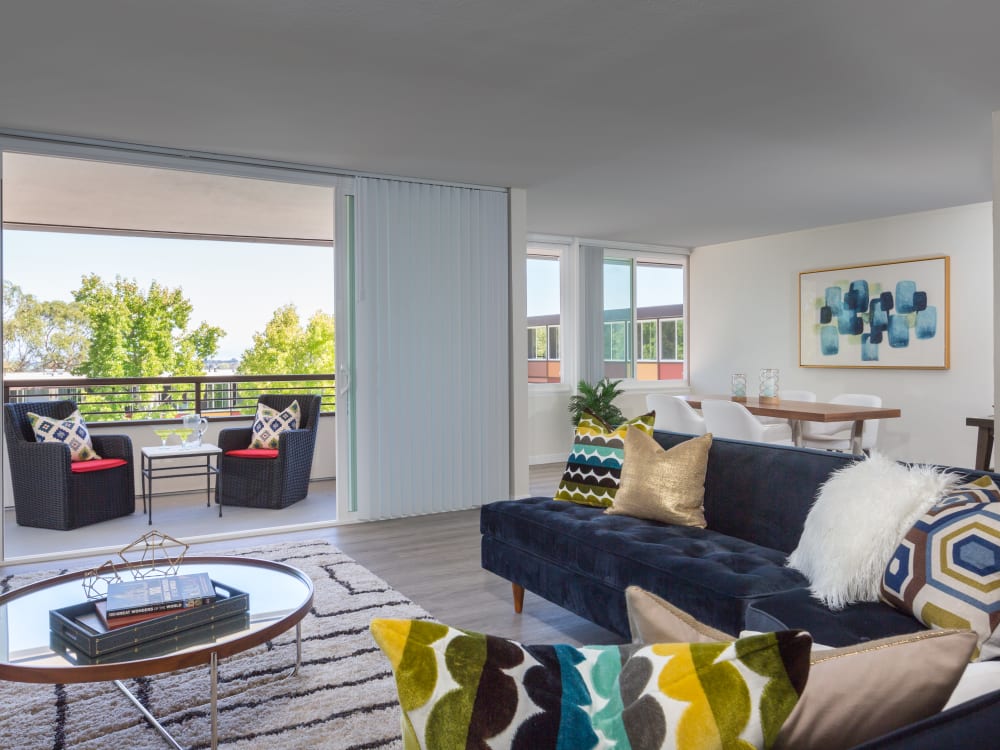 Spacious living area looking out onto the well-decorated private balcony outside a model home at Sofi Belmont Glen in Belmont, California