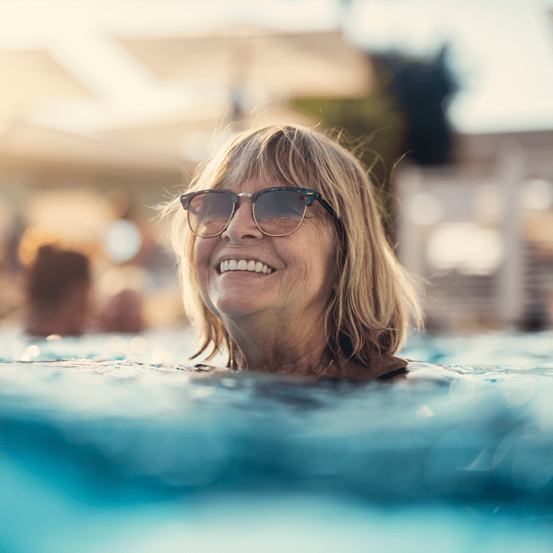Resident smiling and swimming in the pool at The Views at Lake Havasu in Lake Havasu City, Arizona