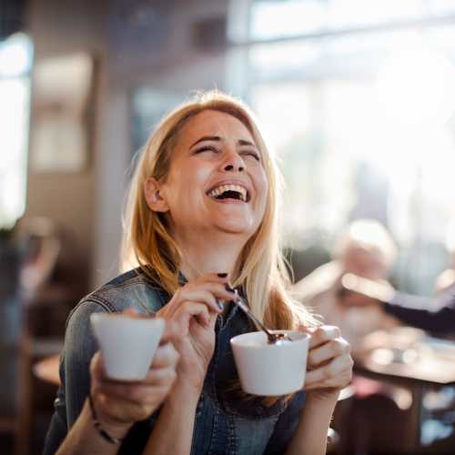 Woman sipping coffee at a café near The Seven At West Boca in Boca Raton, Florida