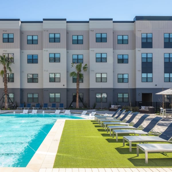 Exterior of townhomes with large community pool and lounge chairs at Bellrock Memorial in Houston, Texas