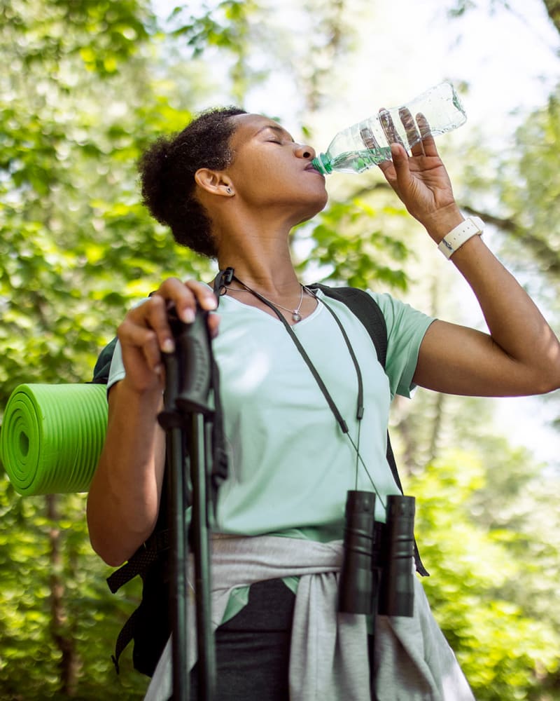 A woman drinking water while on a hike near The Residence at Patriot Place in Columbus, Georgia