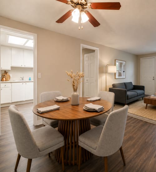 Dining area with round table, four chairs, ceiling fan, and open layout to kitchen and living room at Creek Hill near Live Louisville Apartments in Louisville, Kentucky