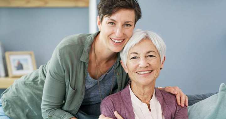 Adult daughter and elderly mother smiling conveying support