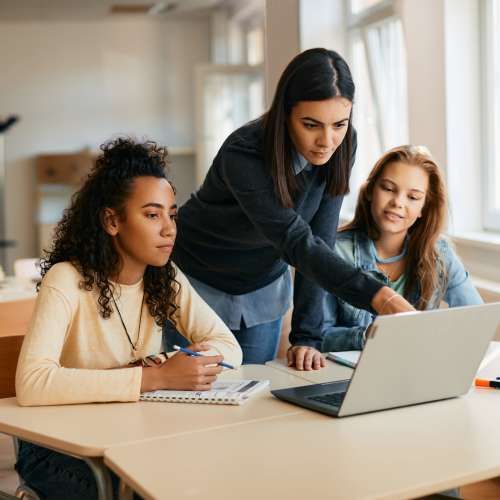 Three women collaborating at a table with a laptop and notebooks, engaged in discussion at Monarch Station in Louisville, Kentucky