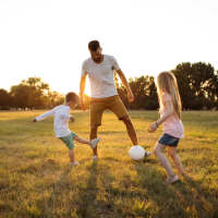 Resident playing football with his children near Lincoln Court Apartments in Dallas, Texas