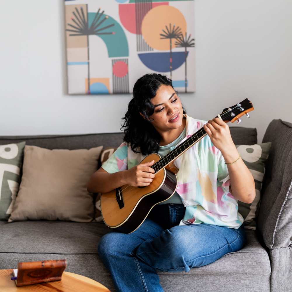 Resident playing guitar in her living room at Tribecca Pointe Apartments in Hurst, Texas