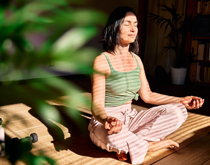 A woman meditating on a yoga mat in her apartment at Forest Place in North Miami, Florida