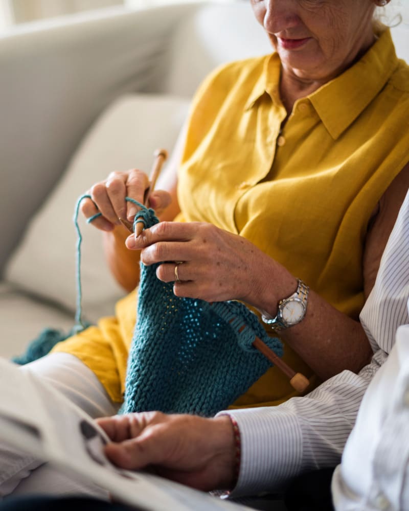 Resident knitting on the couch at Randall Residence at Encore Village in Brighton, Michigan