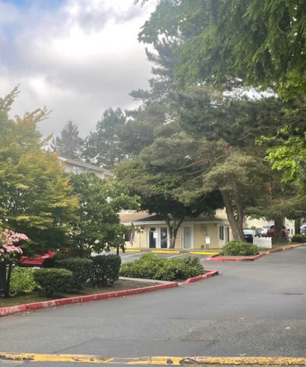 Grassy walking path with trees surrounding at at Amber Glen Apartments in Everett, Washington