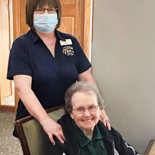 Masked caretaker with a resident at Glen Carr House Memory Care in Derby, Kansas